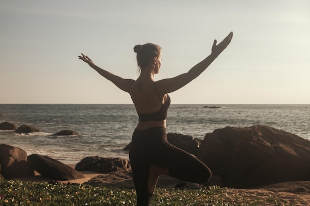 Young woman does yoga for healthy lifestyle on sea beach