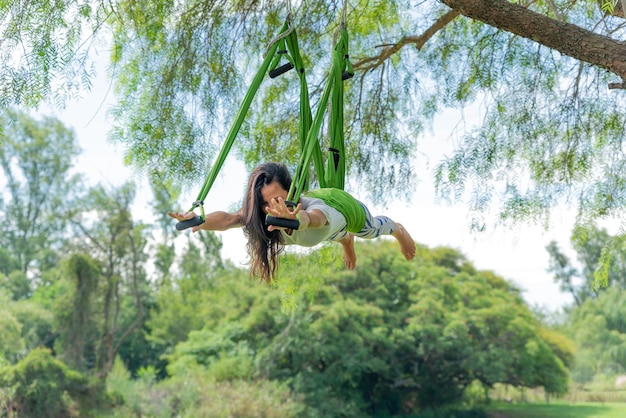 Young Woman Doing Aerial Yoga in a Green Park