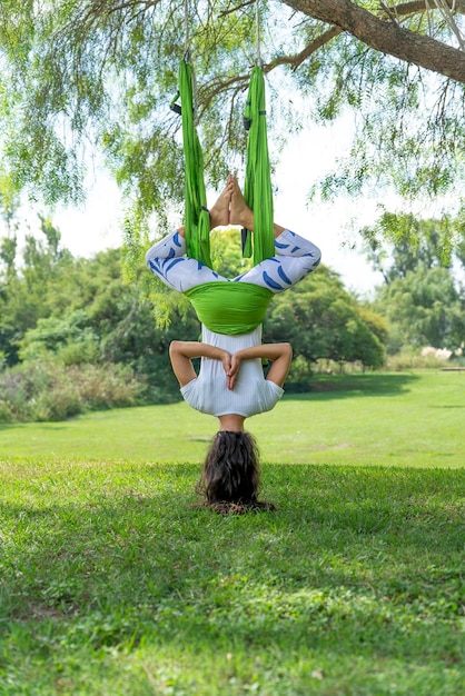 Young Woman Doing Antigravity Yoga exercise in a ParkVertical Image