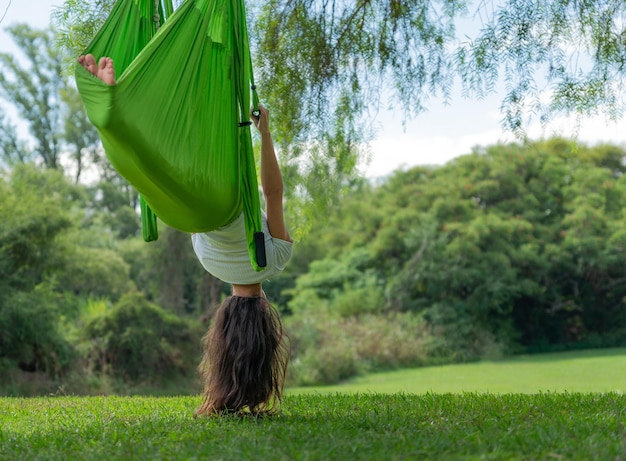 Young Woman Doing Antigravity Yoga in a Park on a Sunny Day