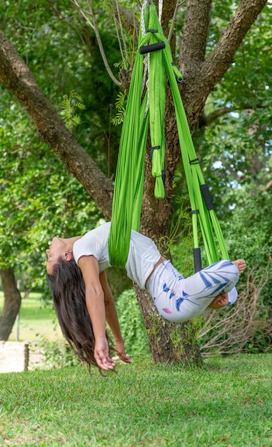 Young Woman Doing Antigravity Yoga in a Park on a Sunny DayVertical Image