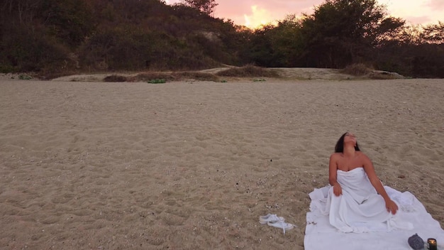 Young woman doing dynamic meditation on the beach in the evening