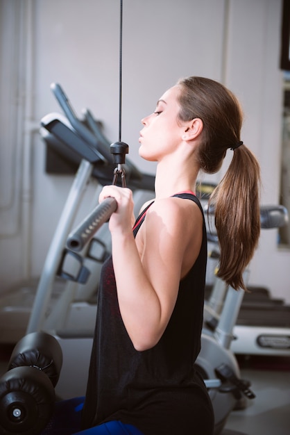 Young woman doing exercises on a machine at the gym