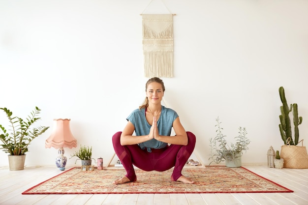 young woman doing garland pose at yoga studio