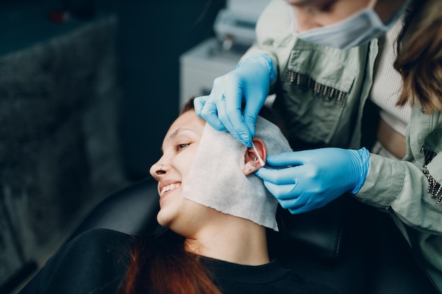 Young woman doing piercing at beauty studio salon