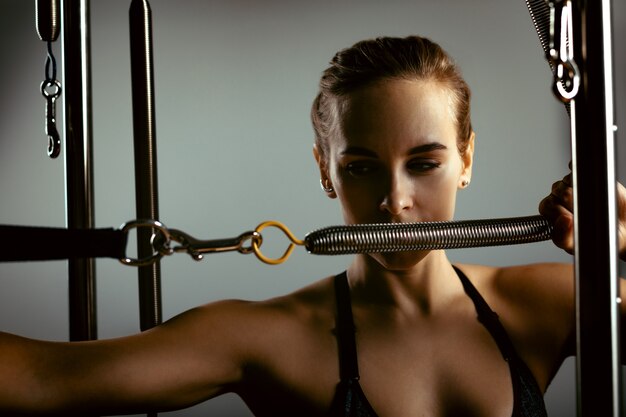 Young woman doing pilates exercises with a reformer bed