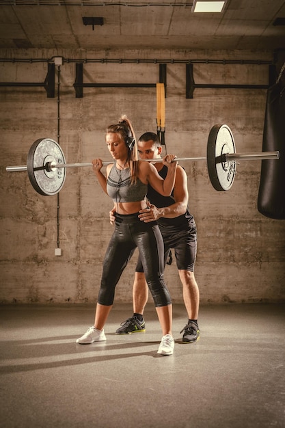 Young woman doing squat exercise at the gym with a personal trainer.