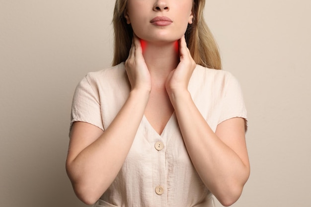 Photo young woman doing thyroid self examination on beige background closeup