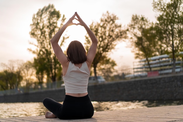 Young woman doing yoga by the lake