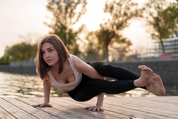 Young woman doing yoga by the lake