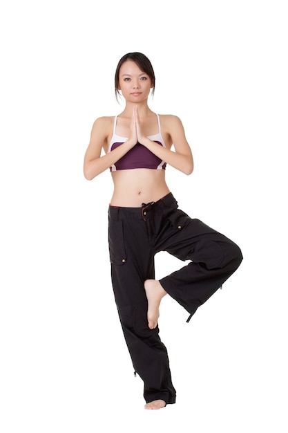 Young woman doing yoga excise by standing on one foot isolated over white.