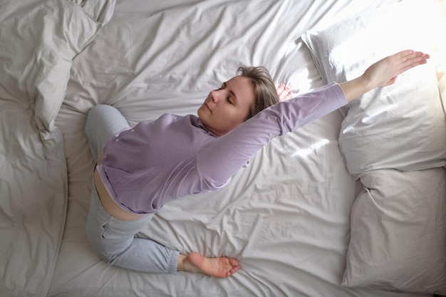 Young woman doing yoga exercise on bed at home