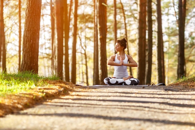 Young woman doing yoga exercises in the autumn city park health lifestyle concept