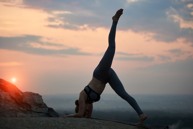 Young woman doing yoga exercises outdoors at sunset