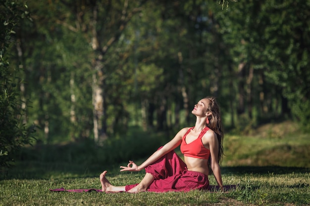 Young woman doing yoga exercises in the summer city park