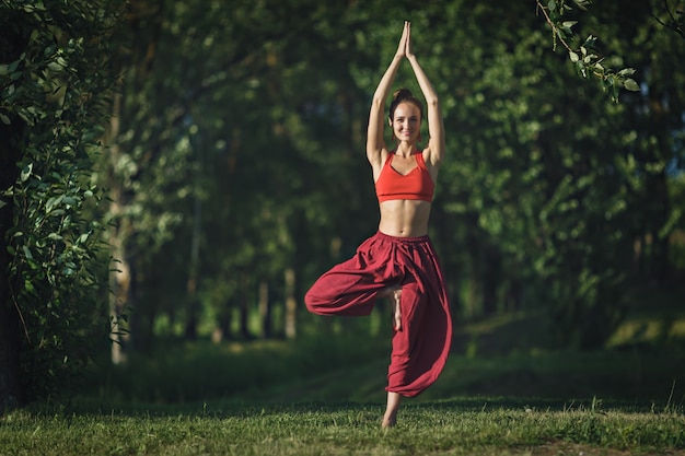 Young woman doing yoga exercises in the summer city park