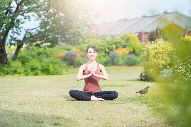 Young woman doing yoga in a green park on fine day