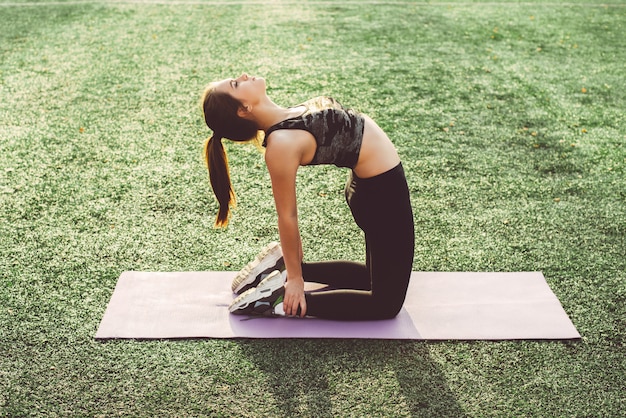  Young woman doing yoga in stadium