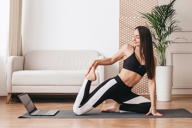 Young woman doing yoga and stretching at home Online pilates and yoga classes