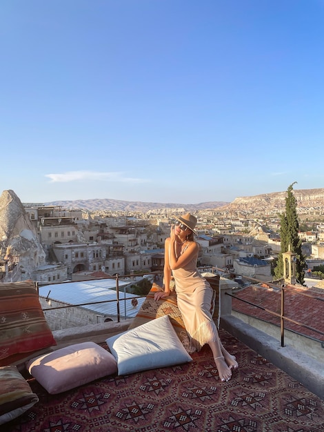 Young woman in dress on the roof with amazing view of Cappadocia in Turkey