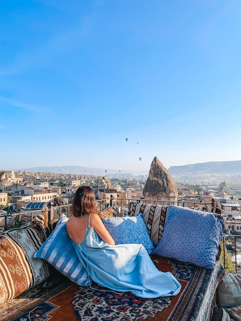 Young woman in dress on the roof with amazing view of Cappadocia in Turkey