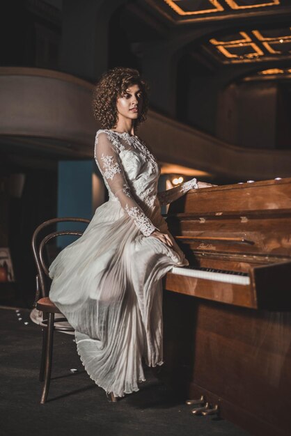 Photo young woman in dress sitting on piano