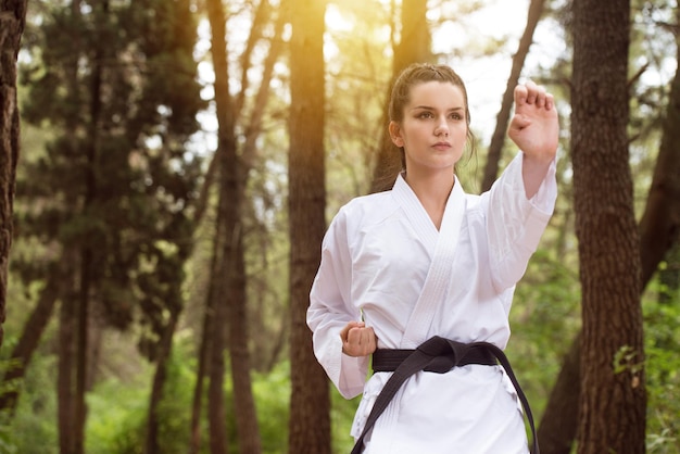 Young Woman Dressed In Traditional Kimono Practicing Her Karate Moves in Wooded Forest Area  Black Belt