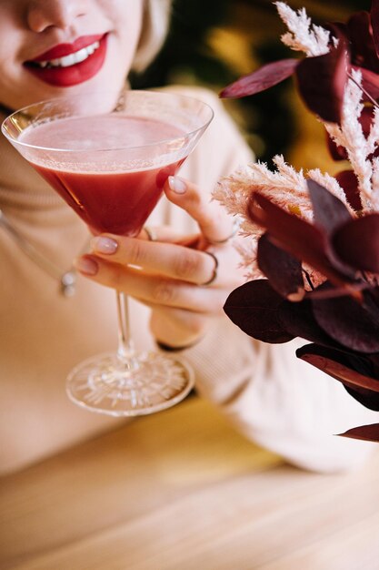 Young woman drink red cocktail with strawberry