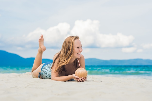 Young woman drinking coconut milk on beach