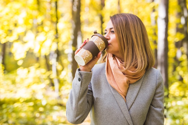 young woman drinking coffee in autumn park