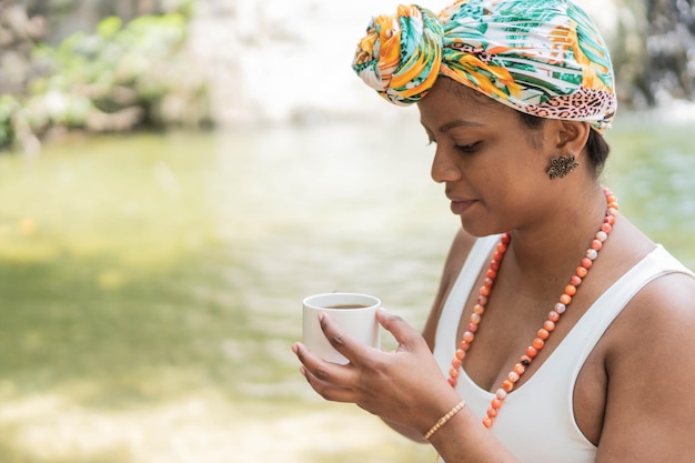 Young woman drinking coffee by the river