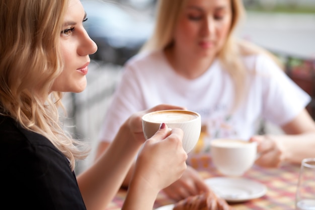 Young woman drinking a coffee in a cafe terrace with friends