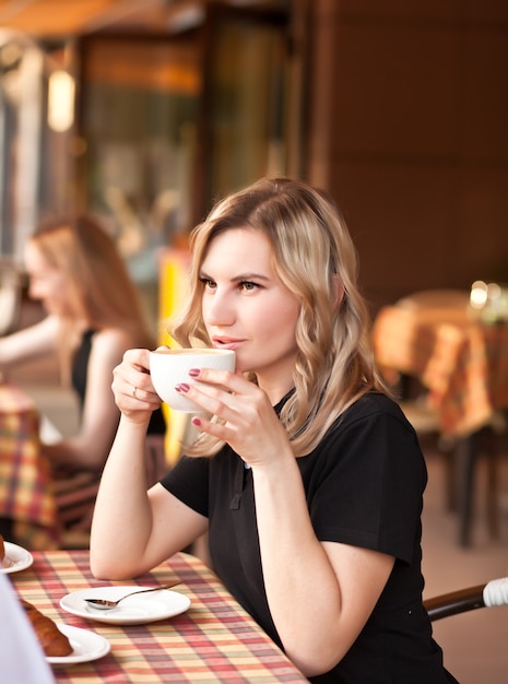 Young woman drinking a coffee in a cafe terrace with friends