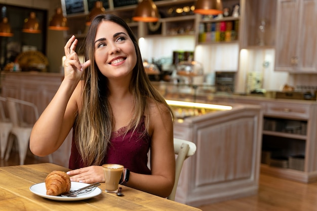 Young woman drinking coffee and making the sign of listening