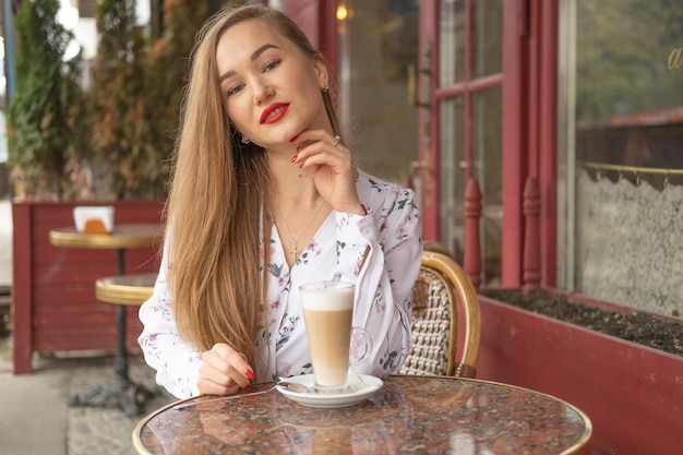 Young woman drinking coffee in a Parisian street cafe