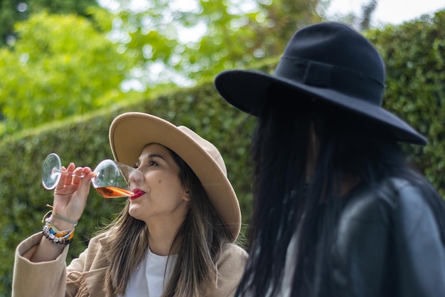 A young woman drinking a glass of wine with a friend in the park