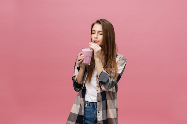 Young woman drinking juice smoothie with straw. Isolated studio portrait.