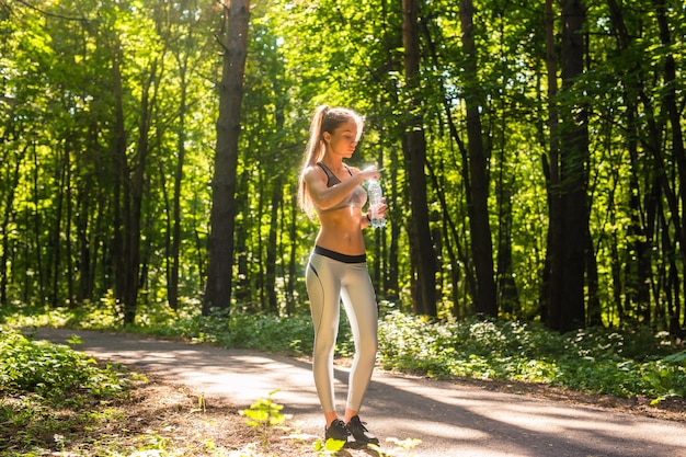 Young woman drinking water after running outdoors.