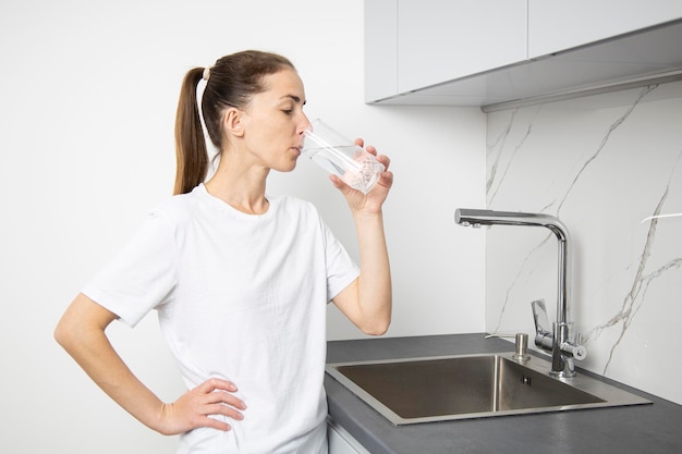 Young woman drinking water from a glass in the kitchen