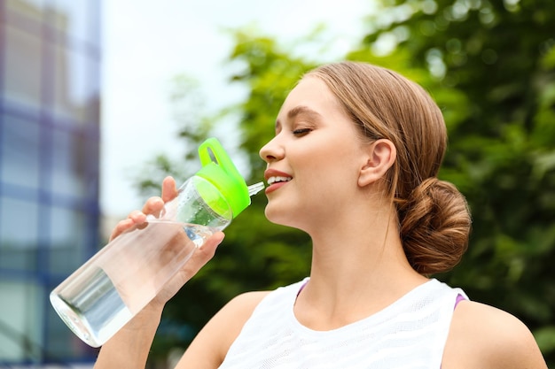 Young woman drinking water outdoors Refreshing drink