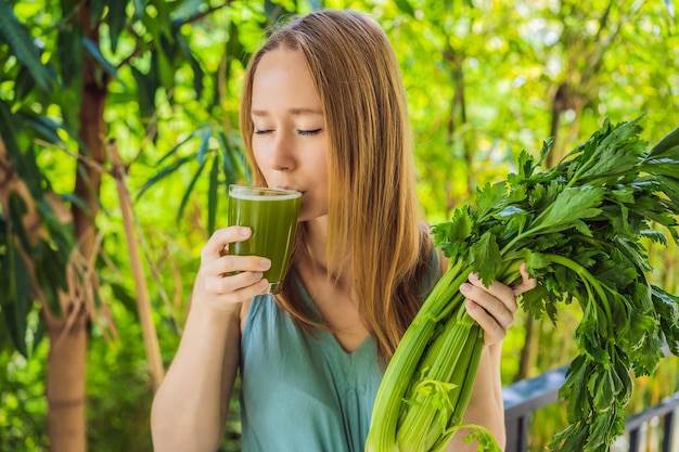 Young woman drinks Celery Juice Healthy Drink bunch of celery on a wooden background