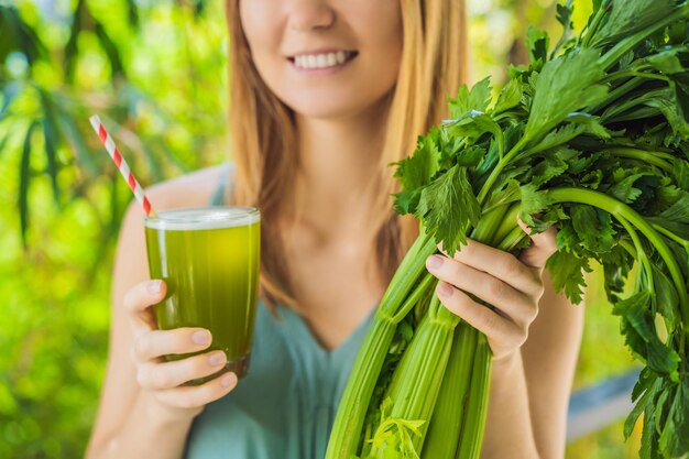 Young woman drinks Celery Juice Healthy Drink bunch of celery on a wooden background