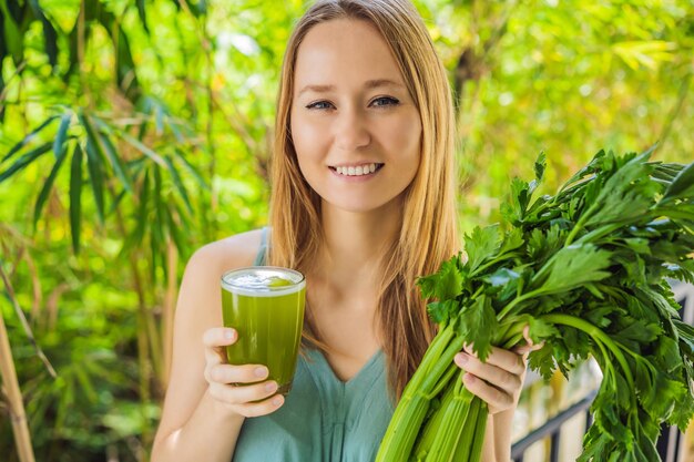 Young woman drinks Celery Juice Healthy Drink bunch of celery on a wooden background