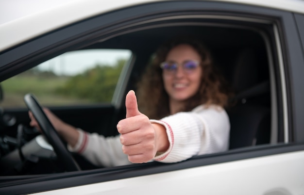 Photo young woman driving is making a thumbs up gesture with her hand