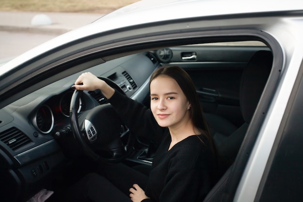 Young woman in a driving school, learning to drive, sitting in a car, smiling