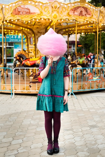 Young woman eating cotton candy in an amusement park