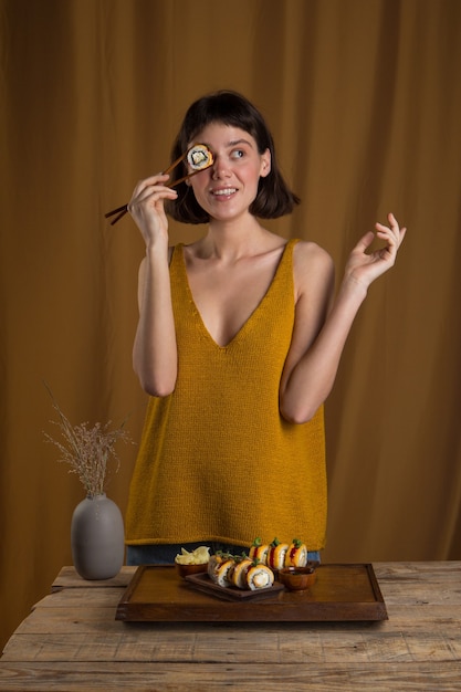 Young Woman eating and enjoying fresh sushi roll using chopsticks