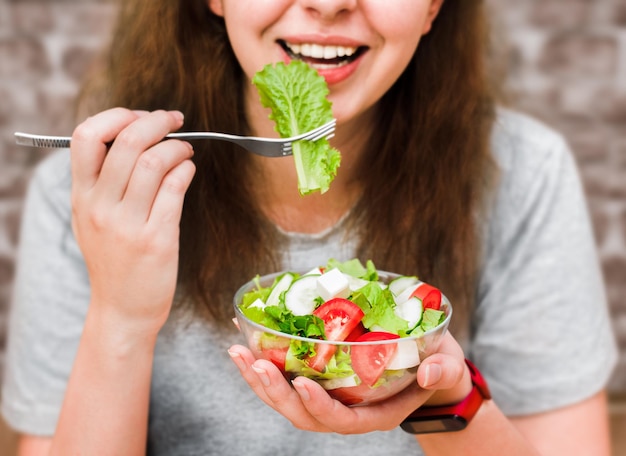 Young woman eating fresh vegetable salad