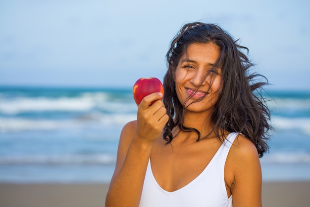 Young woman eating fruit on the beach