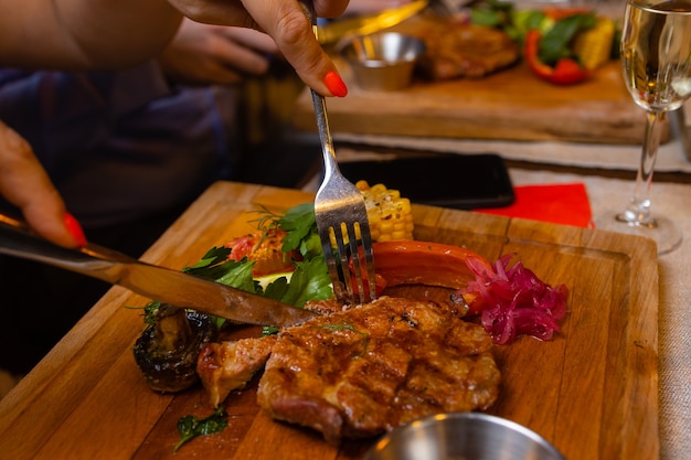 Young woman eating grilled steak in restaurant